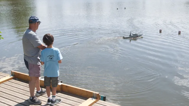 Un adhérent adulte apprend à un jeune garçon de 8 ans à piloter une maquette radiocommandée.